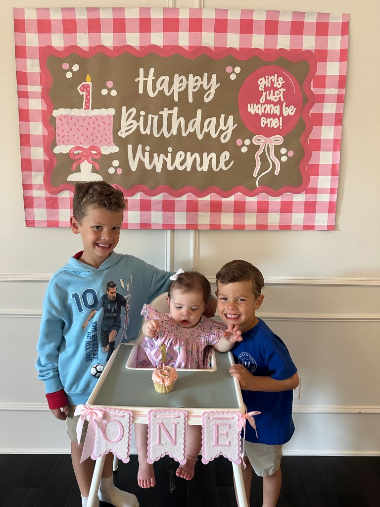 Luke's children celebrating Vivienne's first birthday with a custom banner